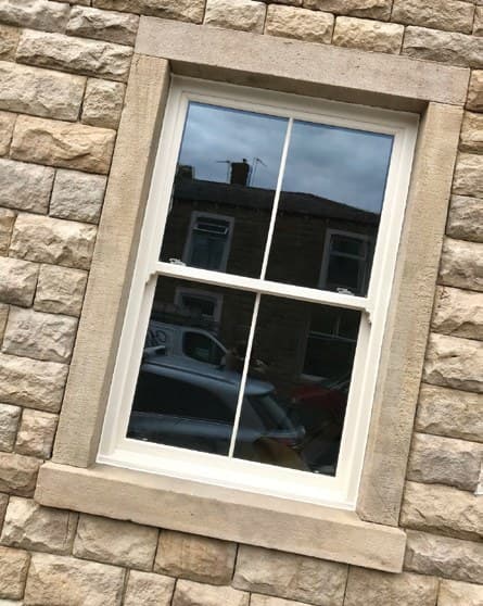 Sliding sash window with Georgian glazing bars in a stone elevation
